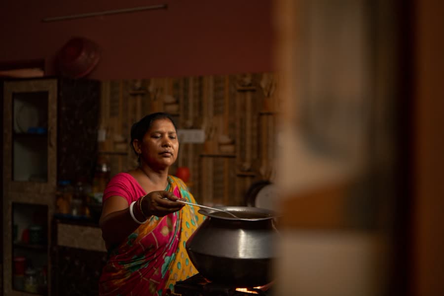 A woman stirring a pot in a warm home kitchen