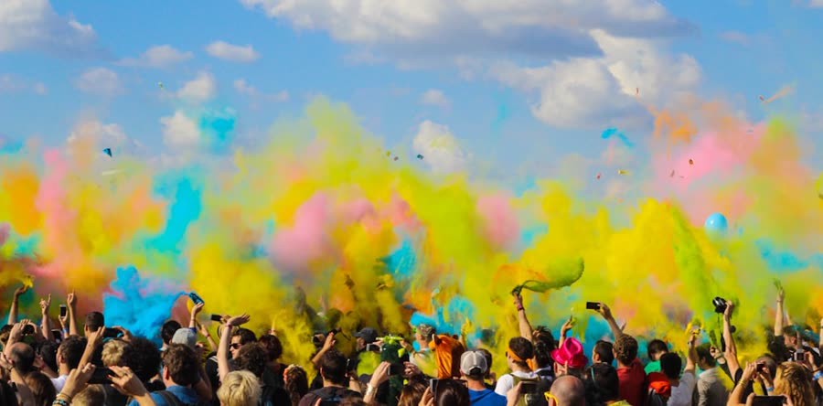 A crowd throwing bright Holi colours into the air